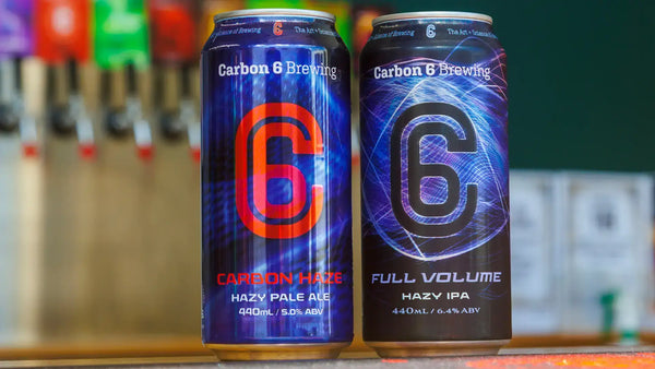 Haze Craze Hazy IPA Carbon 6 Brewing cans displayed on bar with colorful background.