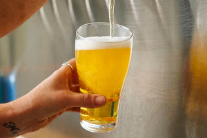 Pouring a cold Carbon 6 Brewing Mid Lager into a glass with frothy head.