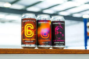 first beers at Carbon 6 Brewing displayed in sleek cans on wooden shelf.