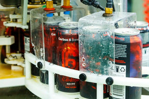 Beer canning process at Carbon 6 Brewing with cans being filled and cleaned in a production line.
