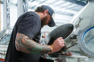 Brewer at Carbon 6 Brewing craft beer examining brewing equipment in a brewery.