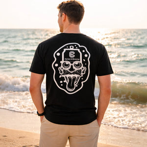 Person wearing the Carbon 6 Can Head Brewer Tee on the beach with ocean waves in the background.